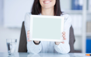 Smiling woman showing a tablet against the blurred background